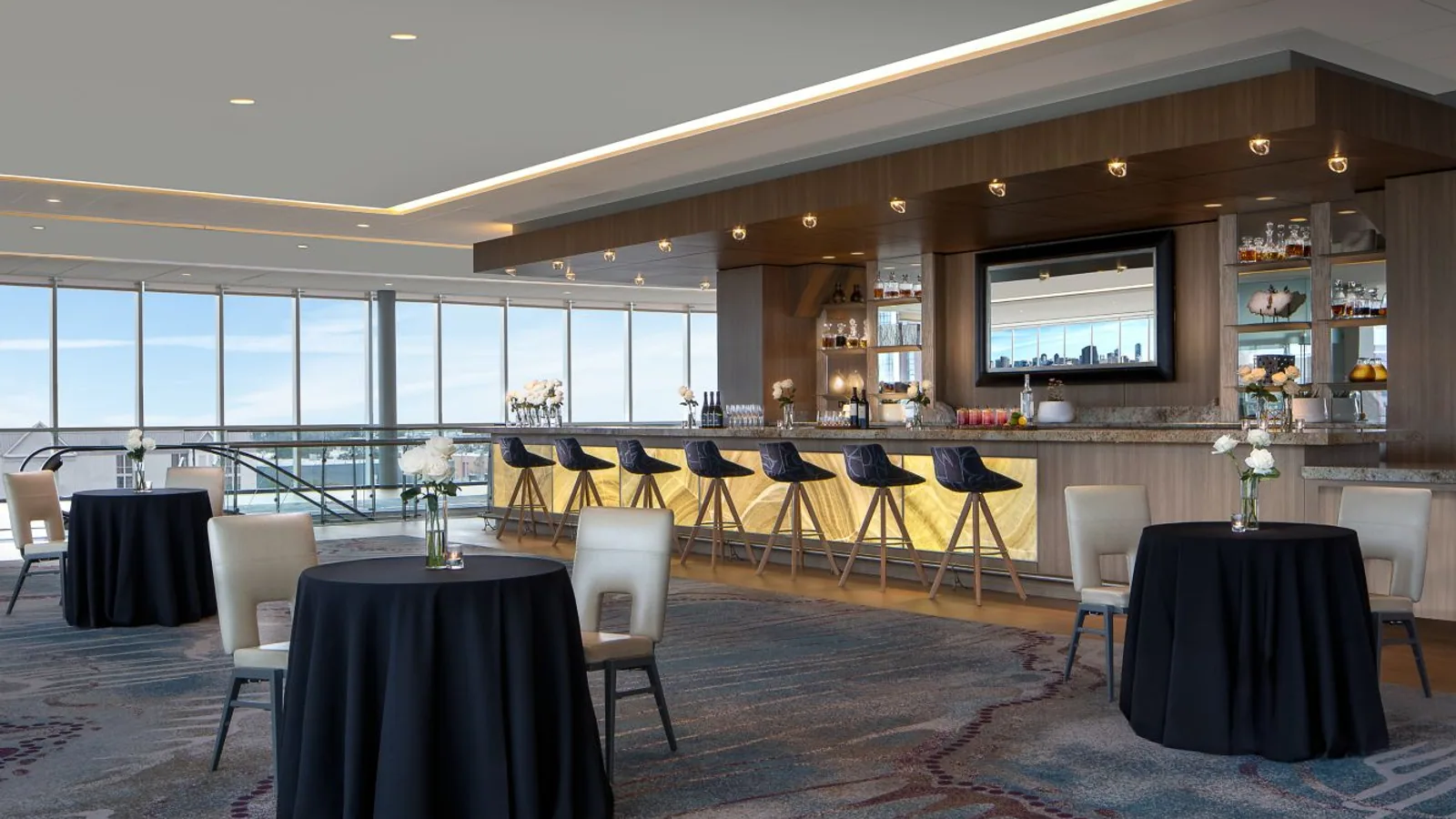 Hospitality event space with a finished bar, panoramic windows, and coordinated wall and ceiling surfaces.