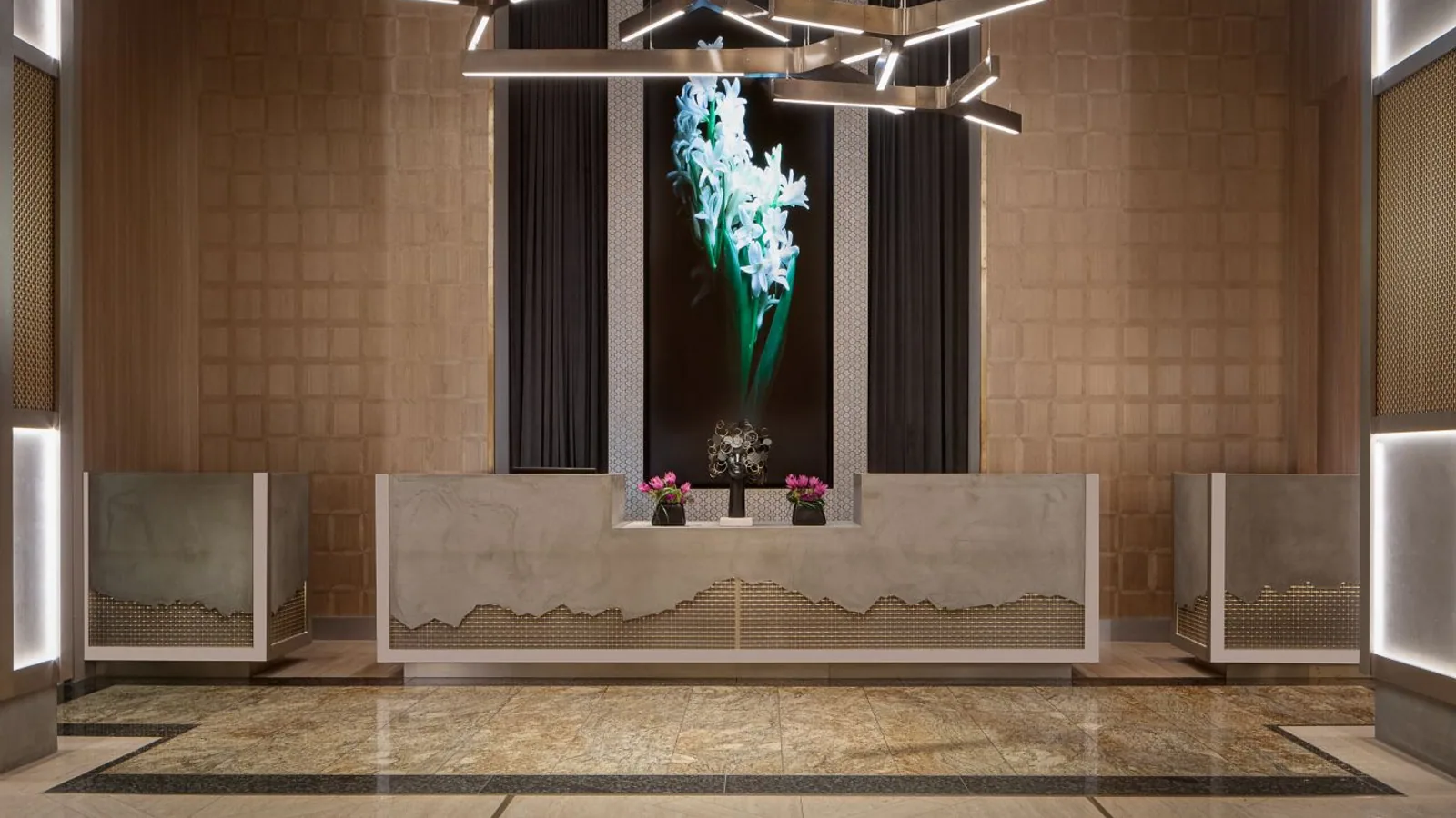 Hotel reception desk framed by patterned wall finishes and sculptural lighting.
