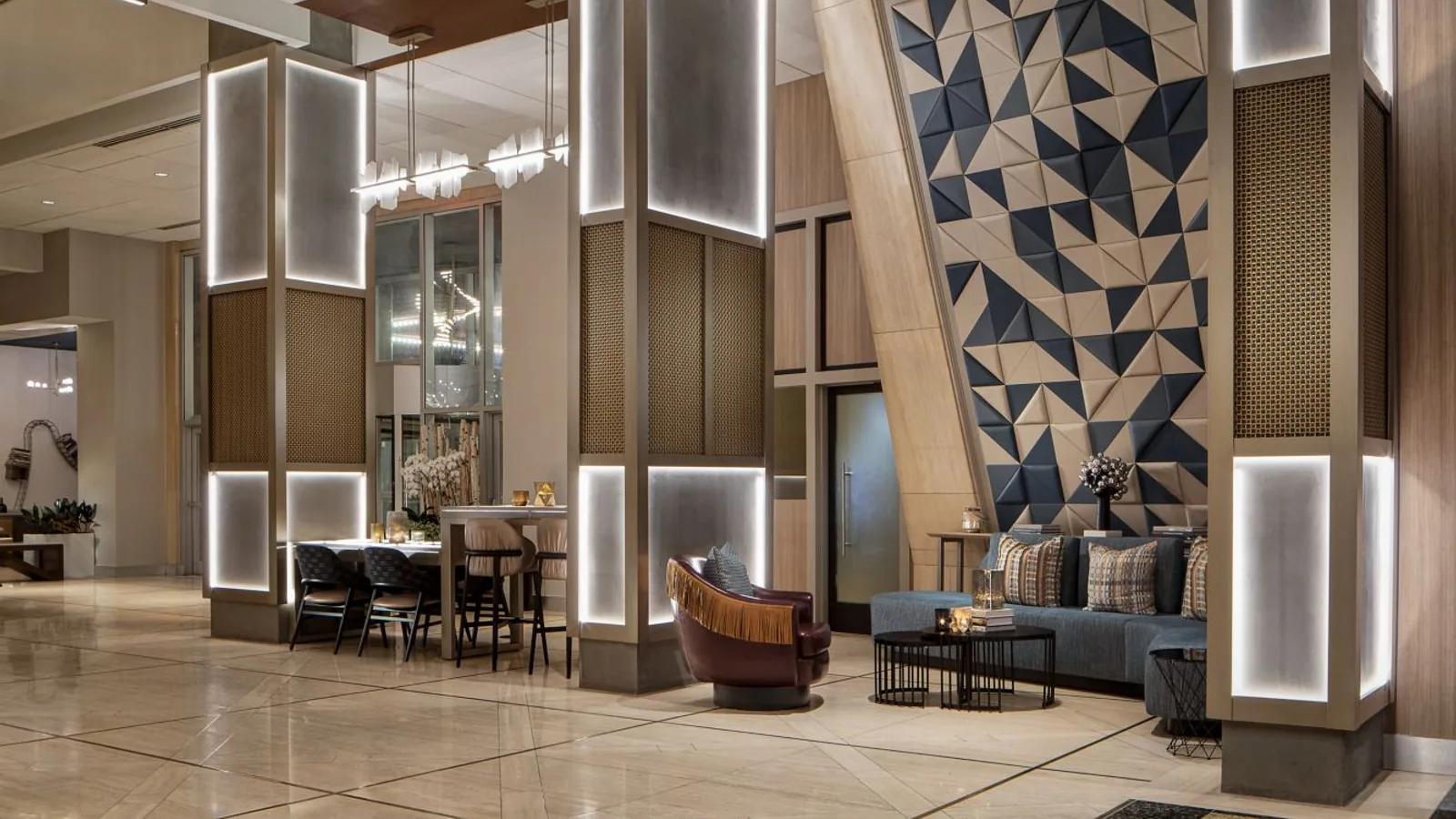 Hotel lobby with illuminated columns and a large blue-and-neutral geometric feature wall.