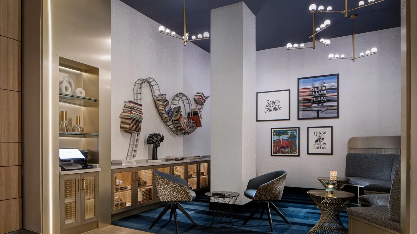 Hotel lounge with light patterned wallcovering, a dark ceiling, and tailored seating.