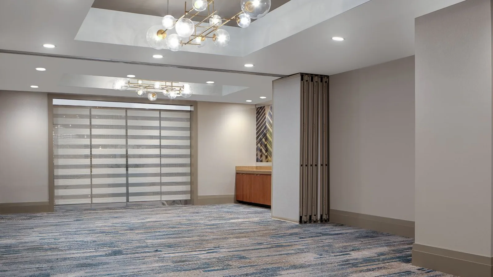 Hospitality meeting room with an operable partition folded into a recessed wall pocket.
