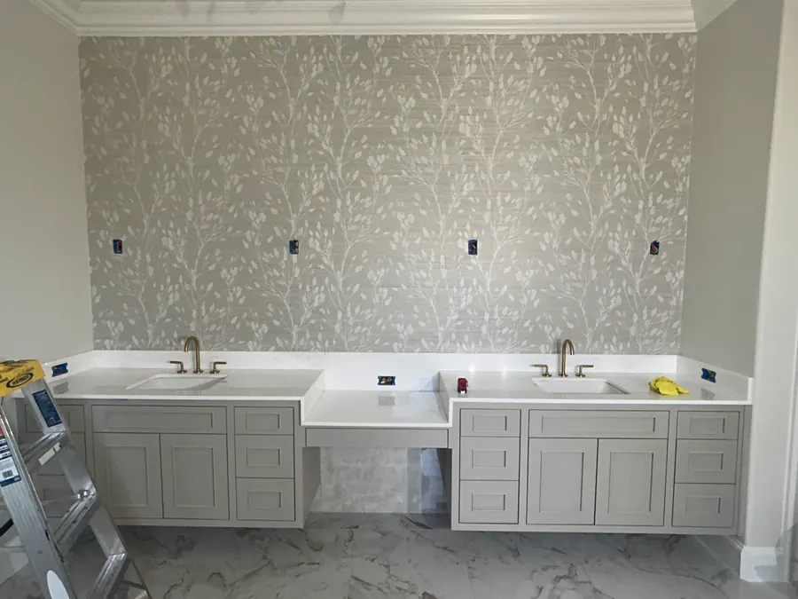 Pale botanical wallcovering installed above a double vanity during a residential bathroom project.