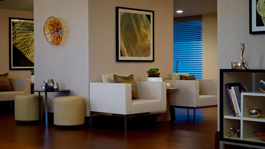 Hotel lounge with light vertical textured wallcovering, white seating, and framed artwork.