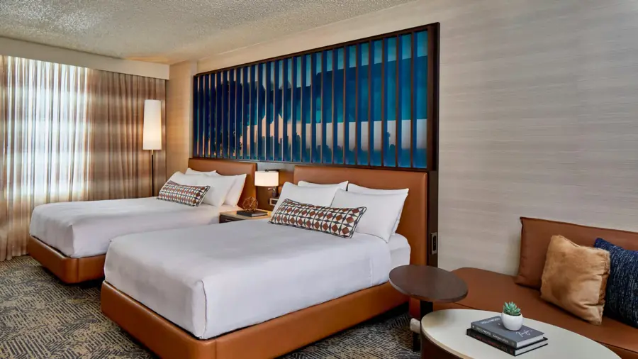 Hotel guestroom with two beds and coordinated neutral wallcovering.