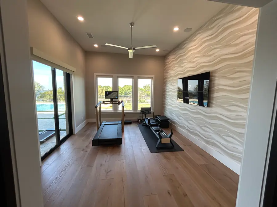 Finished room with a sculptural white wave-pattern wallcovering feature wall beside a wall-mounted television.