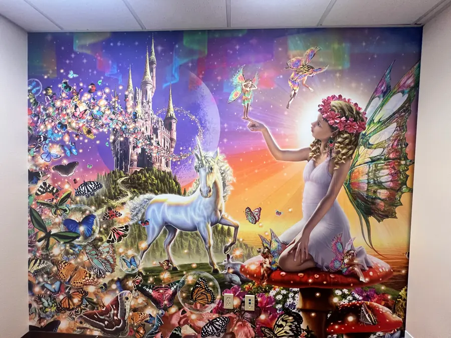 Colorful fairytale mural wallcovering with a castle, butterflies, a unicorn, and winged figures.