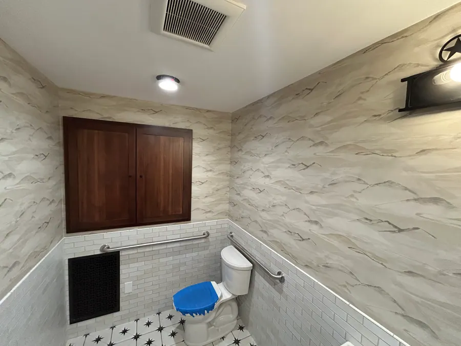 Soft gray mountain mural wallcovering installed above white tile in a residential bathroom.