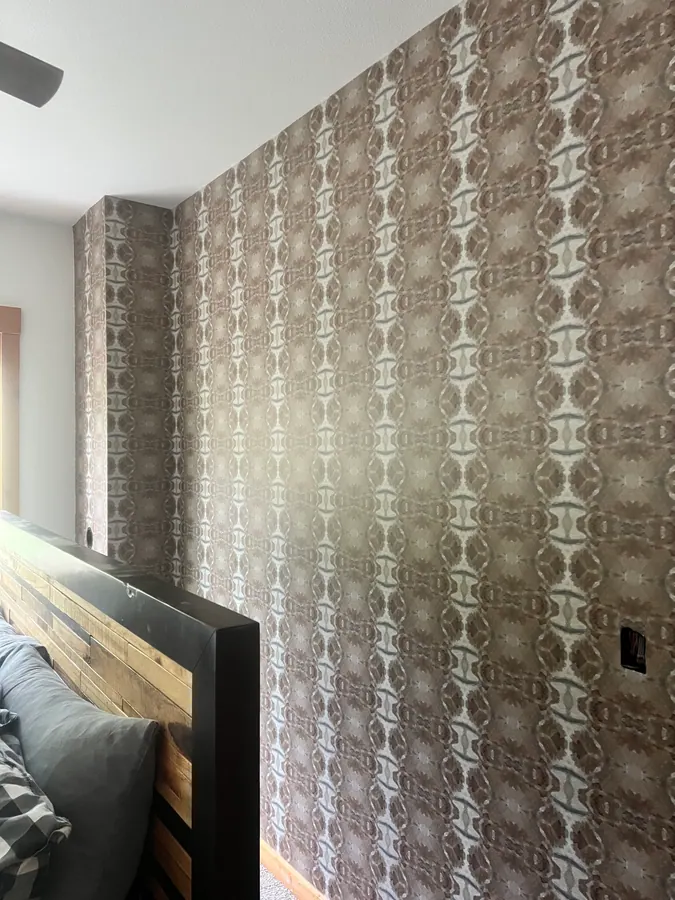 Taupe patterned wallcovering installed across a bedroom feature wall and wrapped around an architectural projection.