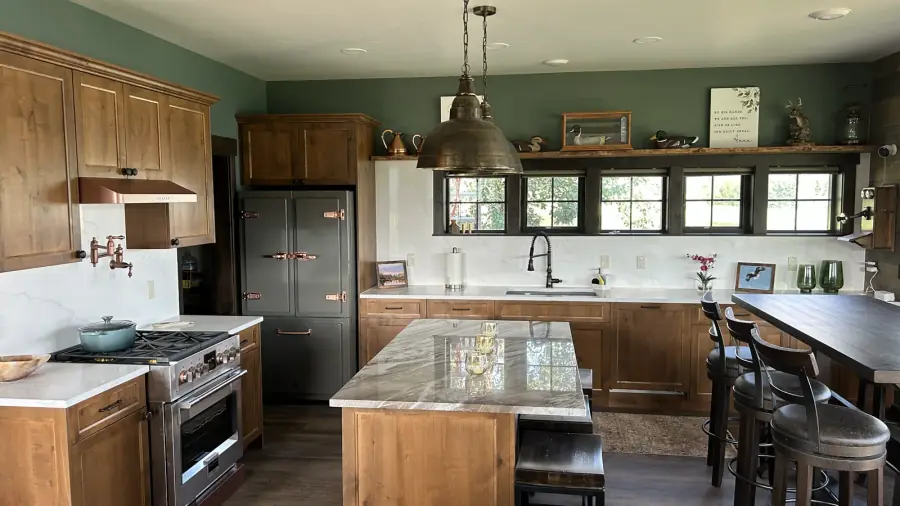 Finished residential kitchen with green painted walls and natural wood cabinetry.