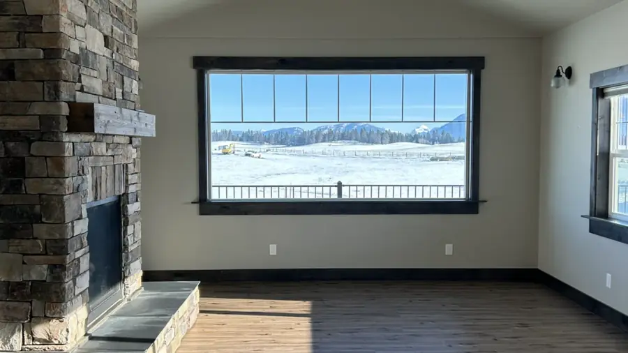 Painted living room with a stone fireplace and mountain views through tall windows.