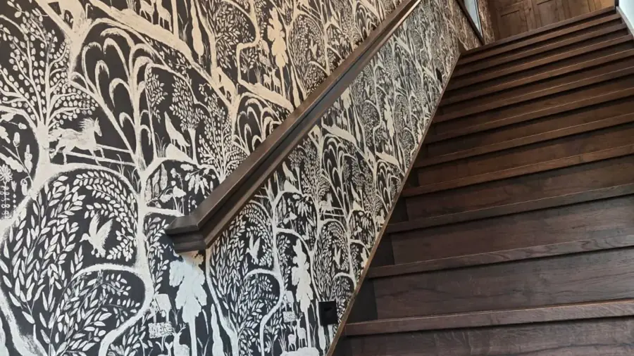 Black-and-white woodland mural wallcovering installed beside a residential staircase.