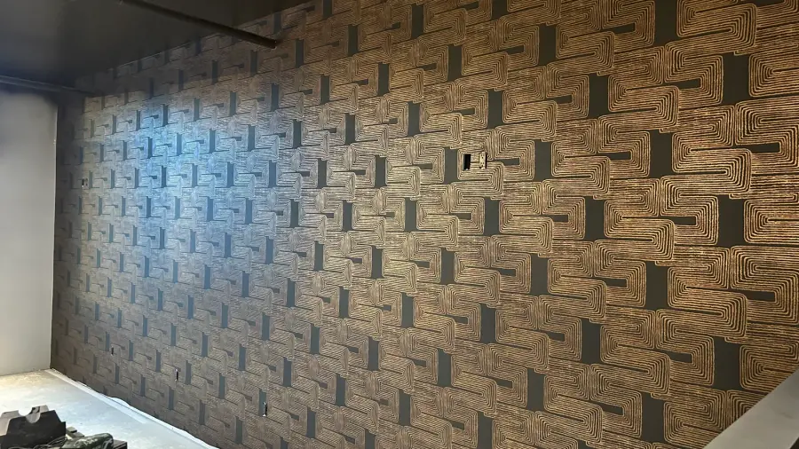 Dark geometric wallcovering installed across a residential feature wall.
