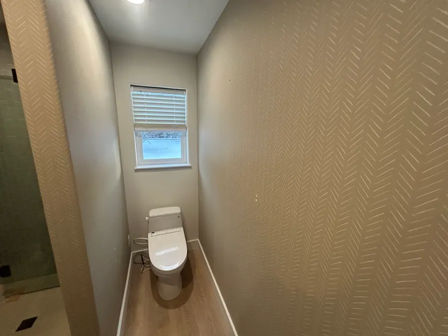 Light neutral wallcovering with a subtle raised chevron pattern installed in a compact powder room.
